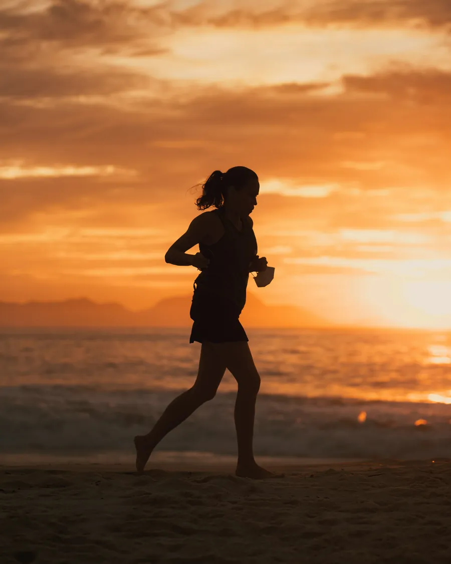 Person running on a beach at sunset
